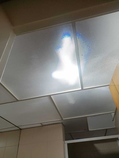 Bright light shining through a textured ceiling panel.