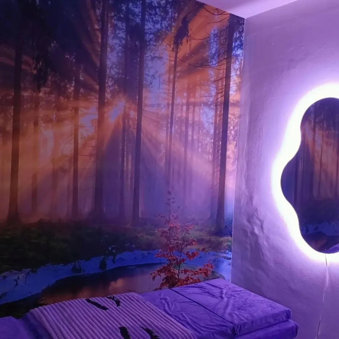 Serene bedroom with forest wall mural and lit mirror